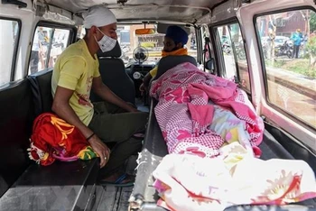 Chuyển thi thể nạn nhân tử vong do bị ngộ độc rượu tới bệnh viện ở Ấn Độ. (Ảnh: AFP/TTXVN)