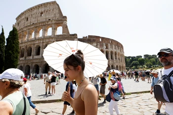 Khách du lịch đi bộ gần Đấu trường La Mã tại Rome trong đợt nắng nóng lan rộng khắp Italia, ngày 17/7/2023. (Ảnh: REUTERS)