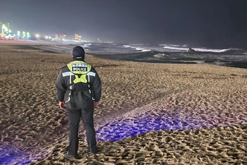Một thành viên của lực lượng bảo vệ bờ biển Hàn Quốc theo dõi thay đổi của mực nước biển trên bãi biển ở Gangneung, Hàn Quốc, ngày 1/1/2024. (Ảnh: Yonhap/AP) 