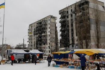 Người dân Ukraine mua thực phẩm tại một khu chợ đường phố phía trước tòa nhà chung cư bị hư hại tại thị trấn Borodianka, tỉnh Kiev, Ukraine, ngày 15/12/2022. (Ảnh: Reuters)