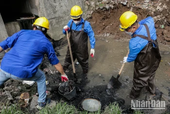 Đoàn viên, thanh niên Báo Nhân Dân và Công ty TNHH MTV Thoát nước Hà Nội tiến hành thu gom, dọn bùn, phế thải tại tuyến phân lũ sông Sét-Lừ. (Ảnh: Nam Nguyễn)