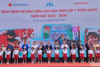 Đại diện Ban tổ chức trao tặng mũ bảo hiểm cho các em học sinh Trường tiểu học Phú Đô (Hà Nội).