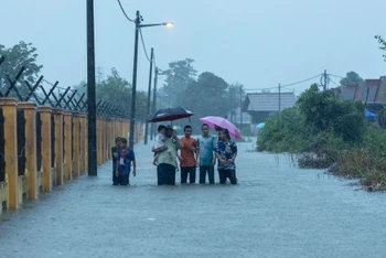 Người dân tại bang Kelantan đi bộ qua vùng lụt để tới Trung tâm cứu hộ. (Ảnh: Malaymail)