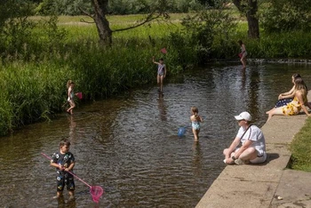Các gia đình tắm mát ở sông Darent ở Eynsford, Anh. (Ảnh: CNN)