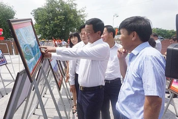 Các đại biểu và nhân dân tham quan gian trưng bày ảnh và tranh tuyên truyền cổ động.