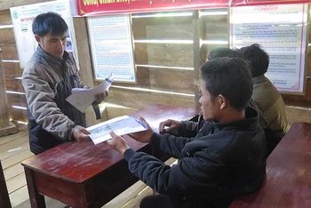 Chính quyền xã Măng Cành, huyện Kon Plông phát Sổ tay phổ biến kiến thức về động đất cho người dân.