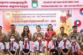Các em học sinh Trường song ngữ Lào-Việt Nam Nguyễn Du tặng hoa tri ân các thầy, cô giáo nhân Ngày nhà giáo quốc gia Lào. (Ảnh: Hải Tiến)