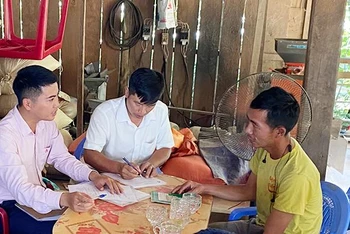 Cán bộ tín dụng Ngân hàng Chính sách xã hội huyện Mường Nhé hỗ trợ người dân bản Cây Sặt, xã Huổi Lếch làm thủ tục vay vốn phát triển chăn nuôi.