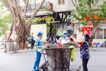 Công nhân Công ty Môi trường đô thị Hà Nội thường xuyên dọn vệ sinh các tuyến đường. (Ảnh PHẠM HÒA)