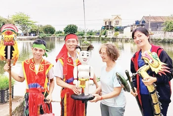 Du khách quốc tế trải nghiệm nghệ thuật rối nước truyền thống cùng các nghệ nhân-nông dân tại xã Hồng Quang, huyện Nam Trực (Nam Định). (Ảnh XUÂN KHÁNH) 