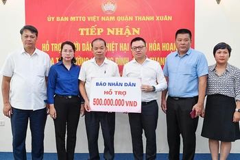 Tổng Biên tập Lê Quốc Minh cùng đoàn Báo Nhân Dân trao 500 triệu đồng hỗ trợ các nạn nhân trong vụ cháy. (Ảnh THÀNH ĐẠT)