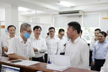 Tổng Giám đốc Bảo hiểm xã hội Việt Nam Nguyễn Thế Mạnh (hàng đầu, bên phải) trao đổi với người dân đến làm việc tại phòng "một cửa" (Bảo hiểm xã hội TP Hồ Chí Minh). (Ảnh TÂM TRUNG)