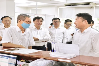 Tổng Giám đốc Bảo hiểm xã hội Việt Nam Nguyễn Thế Mạnh (ngoài cùng, bên phải) trao đổi với người dân đến làm việc tại Bảo hiểm xã hội Thành phố Hồ Chí Minh.