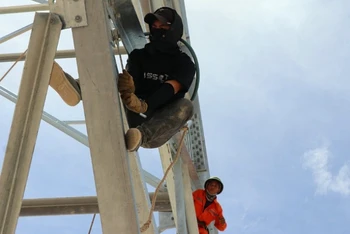 Công nhân cheo leo trên độ cao hàng chục mét để lắp dựng cột trong thời tiết nắng nóng gay gắt của mùa hè xứ Nghệ.