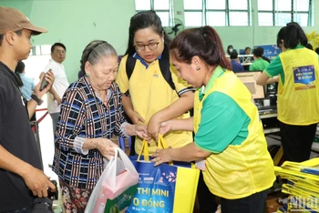 Các tình nguyện viên hỗ trợ một cụ bà mua sắm tại siêu thị 0 đồng.