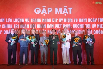 Thượng tướng Trịnh Văn Quyết trao biểu trưng và hoa tặng các nhà văn lực lượng vũ trang tiêu biểu. (Ảnh: Báo Quân đội nhân dân)