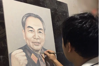 Nghệ nhân Bùi Văn Bến say sưa vẽ tranh chân dung Đại tướng Võ Nguyên Giáp trên nền sứ.