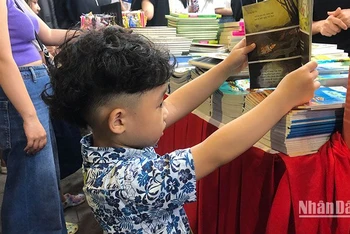 Em bé say sưa xem sách tại Hội sách Hà Nội 2022.