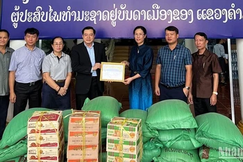 Tổng Lãnh sự quán Việt Nam tại Savnannakhet hỗ trợ người dân chịu ảnh hưởng bởi lũ lụt tại Trung Lào. (Ảnh: Hải Long)