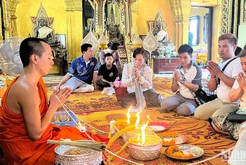 Người dân Lào tham gia nghi lễ buộc chỉ cổ tay đón năm mới 2567 theo Phật lịch của Lào. Ảnh: Trịnh Dũng