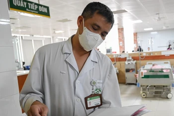 Bác sĩ Nguyễn Trung Nguyên xem hồ sơ bệnh án của bệnh nhân.