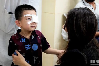 Trẻ bị đau mắt đỏ vừa được bác sĩ bóc giả mạc. (Ảnh: THẾ KHẢI)