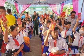 Học sinh biên giới tham dự chương trình chợ Tết yêu thương và nhận bao lì xì từ tay các bộ, chiến sĩ Đồn Biên phòng Sông Trăng, Long An trao. 