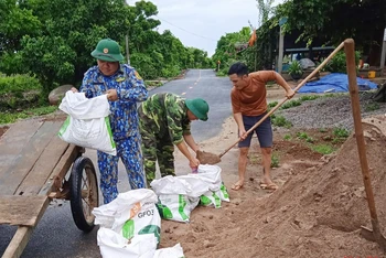 Bộ đội Biên phòng Đảo Cồn cỏ và các lực lượng chức năng giúp người dân tải cát chằng chống mái nhà.