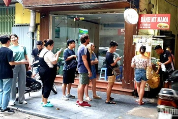 Du khách nước ngoài đứng xếp hàng mua bánh mỳ tại một cửa hàng trên phố Lý Quốc Sư, Hà Nội. (Ảnh: T.LINH)