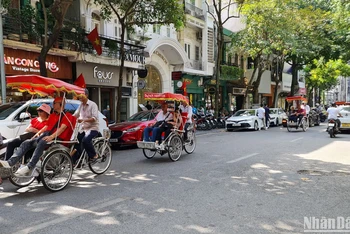 Khách du lịch nước ngoài tham quan phố cổ Hà Nội bằng xe xích lô. (Ảnh: T.LINH)