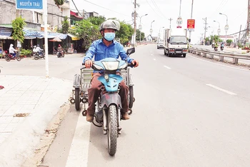 Ông Út lái xe tự chế hút đinh trên Quốc lộ 91, tỉnh An Giang.