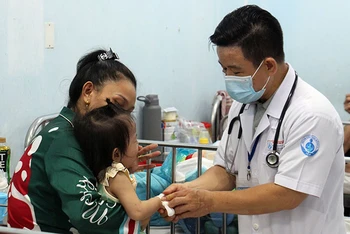 Bác sĩ Bệnh viện Nhi đồng 1 Thành phố Hồ Chí Minh thăm khám cho trẻ mắc tay chân miệng. (Ảnh THẾ ANH)