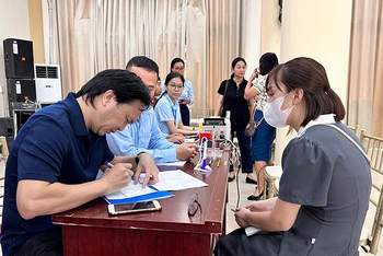Cán bộ quận Thanh Xuân hướng dẫn, hỗ trợ người dân làm thủ tục nhận tiền hỗ trợ.