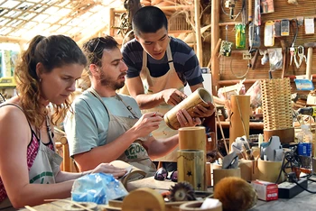 Nhân viên xưởng Taboo Bamboo hướng dẫn du khách hoàn thiện sản phẩm bằng tre. (Ảnh THỦY NGUYÊN)
