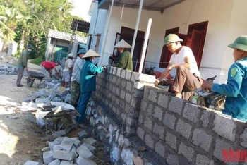 Cán bộ, đảng viên xã Sơn Châu giúp các hộ dân xây dựng lại tường rào sau khi hiến đất mở rộng đường.