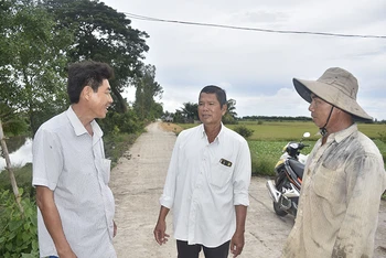 Ông Lương Văn Tạo (ở giữa), Bí thư Chi bộ, Trưởng ấp Sóc Cung tuyên truyền cho người dân về ý nghĩa của việc hiến đất làm đường giao thông nông thôn.