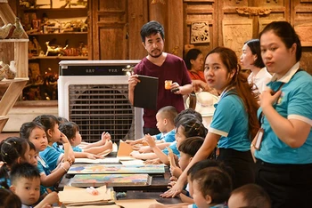 Nghệ nhân Nguyễn Tấn Phát hướng dẫn các em nhỏ thực hành làm tranh in khắc gỗ.