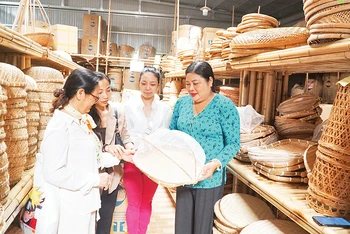 Nghệ nhân Trương Thị Bạch Thủy (bên phải) giới thiệu với du khách tham quan tại phòng trưng bày sản phẩm của Hợp tác xã Mây tre đan Thủy Tuyết.