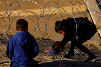 Một cậu bé di cư cố gắng vượt qua hàng rào thép gai do Lực lượng Vệ binh Quốc gia Texas đặt tại biên giới giữa Hoa Kỳ và Mexico với mục đích củng cố an ninh biên giới và ngăn chặn người di cư vượt biên vào Hoa Kỳ, ngày 7/1/2023. Ảnh: REUTERS