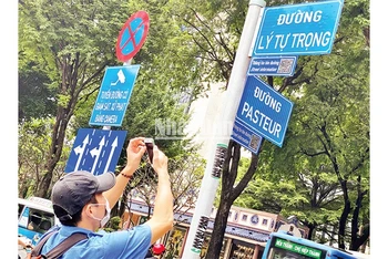 Một du khách tra cứu thông tin tên đường từ mã QR gắn ở giao lộ Lý Tự Trọng-Pasteur, quận 1, TP Hồ Chí Minh.