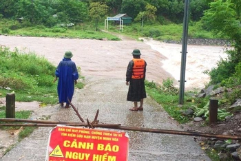 Lực lượng chức năng đặt biển cảnh báo và cử tổ công tác cảnh giới đoạn đường ngập sâu ở huyện Minh Hóa.