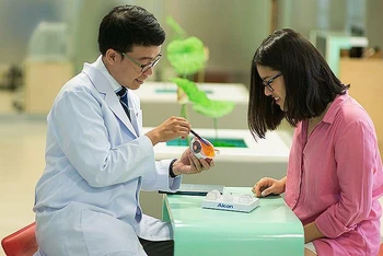TS, BS Trần Đình Minh Huy (bên trái) chăm sóc, giải đáp thắc mắc của người bệnh. 