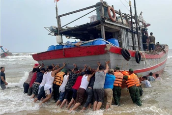 Các lực lượng chức năng và người dân tham gia cứu hộ tàu cá TTH-923.49 TS bị mắc cạn ở bờ biển thôn Cự Lại Nam, xã Phú Hải, huyện Phú Vang.