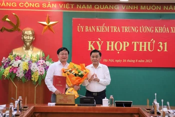 Đồng chí Trần Cẩm Tú, Ủy viên Bộ Chính trị, Bí thư Trung ương Đảng, Chủ nhiệm Ủy ban kiểm tra Trung ương trao quyết định và tặng hoa chúc mừng đồng chí Nguyễn Văn Quyết.