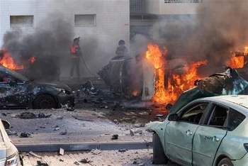 Người dân dập các đám cháy trên xe ôtô sau vụ tấn công bằng rocket từ Dải Gaza tại Ashkelon (Israel), ngày 7/10/2023. (Ảnh: AFP/TTXVN)