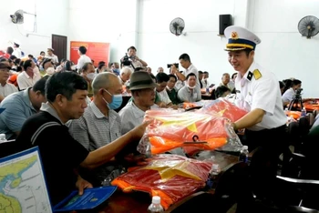 Cán bộ, chiến sĩ Vùng 2 Hải quân trao cờ Tổ quốc cho ngư dân thị xã La Gi (Bình Thuận).