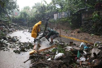 Người dân El Salvador dọn dẹp tuyến đường chịu ảnh hưởng của bão Julia. (Ảnh: Reuters)