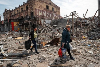 Người dân mang theo đồ đạc rời khỏi tòa nhà tại thành phố cảng Mariupol, Ukraine, ngày 10/4/2022. (Ảnh: Reuters)