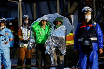Người dân choàng chăn bạc giữ nhiệt theo dõi hoạt động cứu nạn tại thành phố Wajima, tỉnh Ishikawa, Nhật Bản, ngày 3/1/2024. (Ảnh: REUTERS)