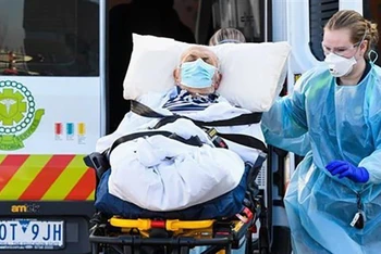 Nhân viên y tế chuyển bệnh nhân Covid-19 tại Melbourne, Australia, trong thời gian đại dịch bùng phát. (Ảnh: AFP/TTXVN)